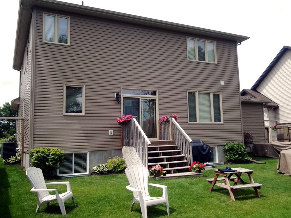 ottawa home with steps leading to backyard with green grass and chairs before custom deck build
