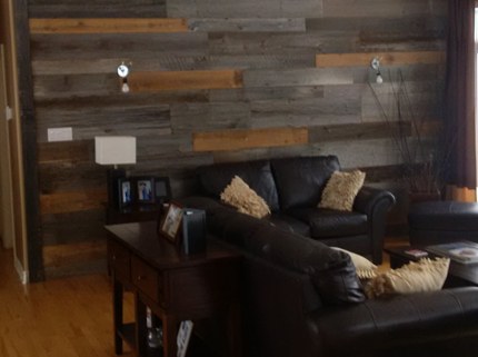living room with black couches and wall with pattern of wooden planks