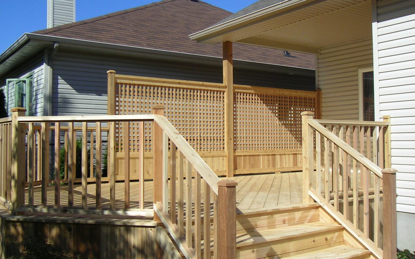Wooden custom deck attached to bungalow with stairs leading to backyard