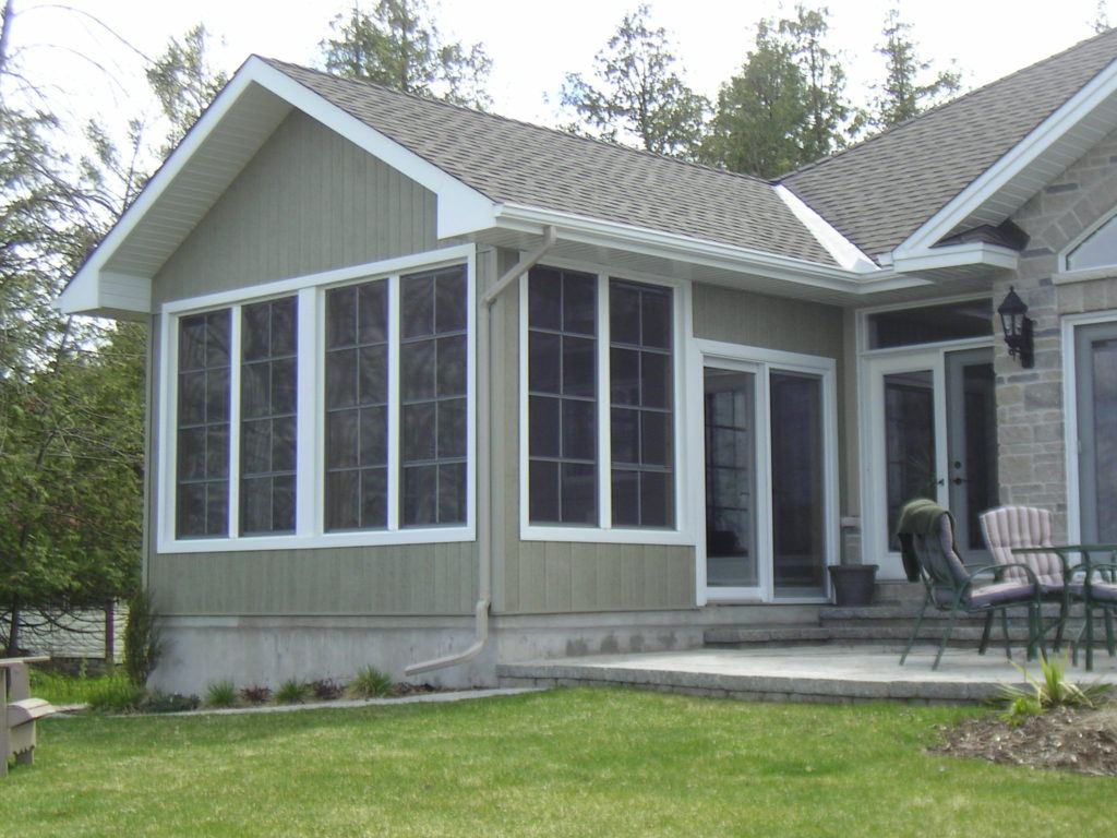 bungalow with large windows and concrete patio with furniture