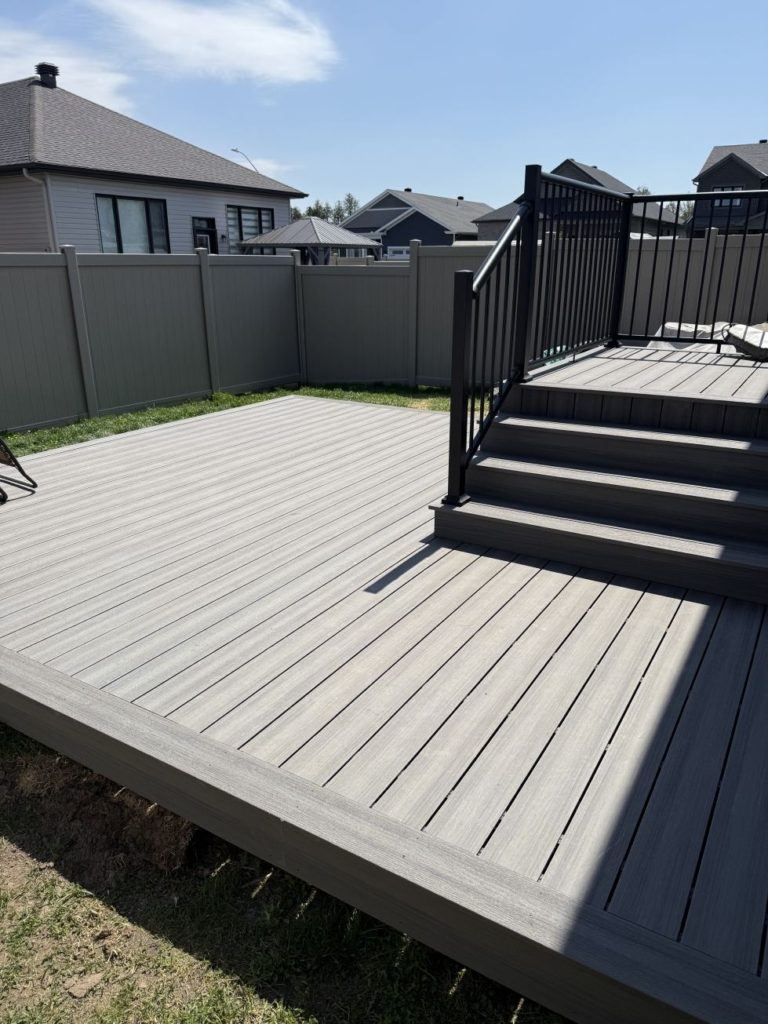 Gray composite deck with steps and black railing.