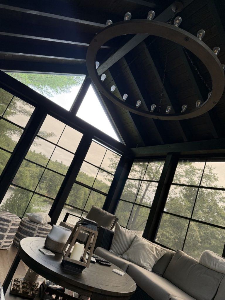 Cozy screened porch with sectional seating and chandelier.