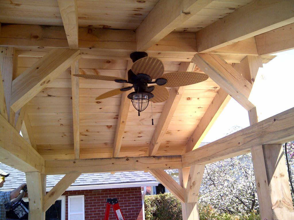 looking up at fan installed in the ceiling of custom wood pergola