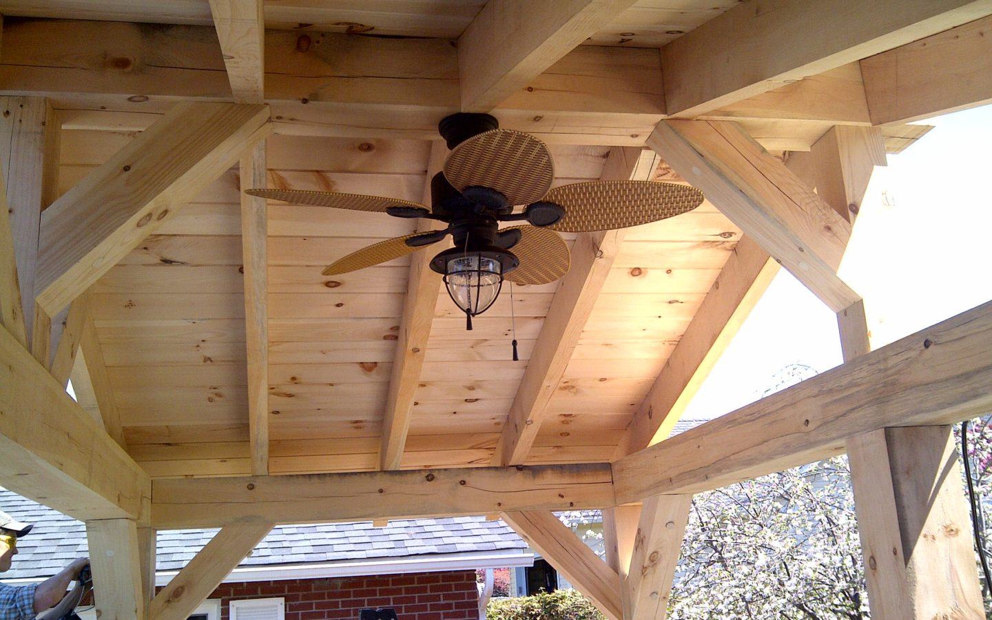 looking up at fan installed in the ceiling of custom wood pergola