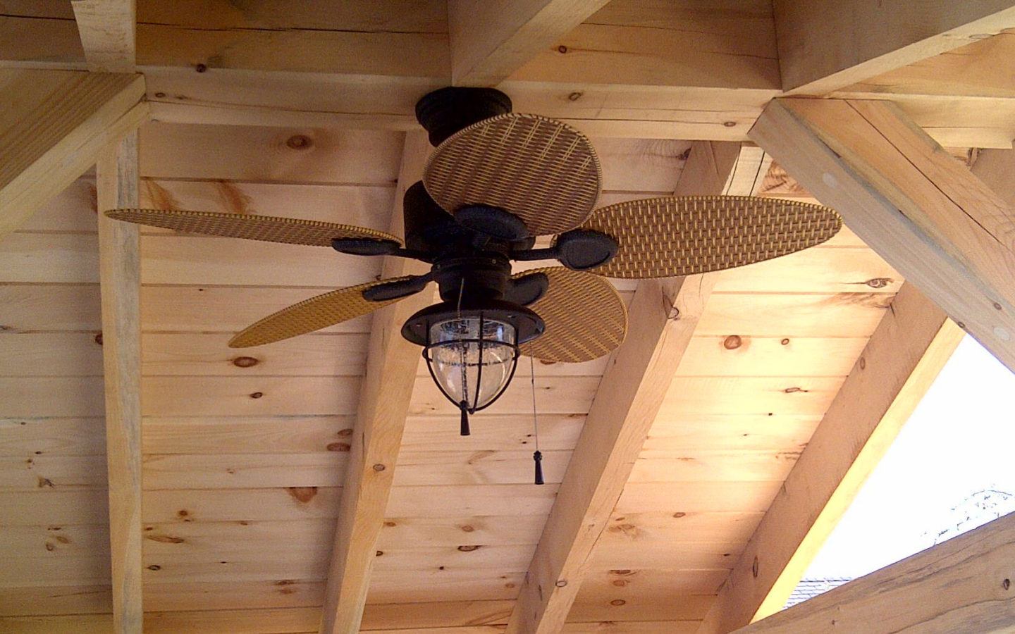 looking up at fan installed in the ceiling of custom wood pergola