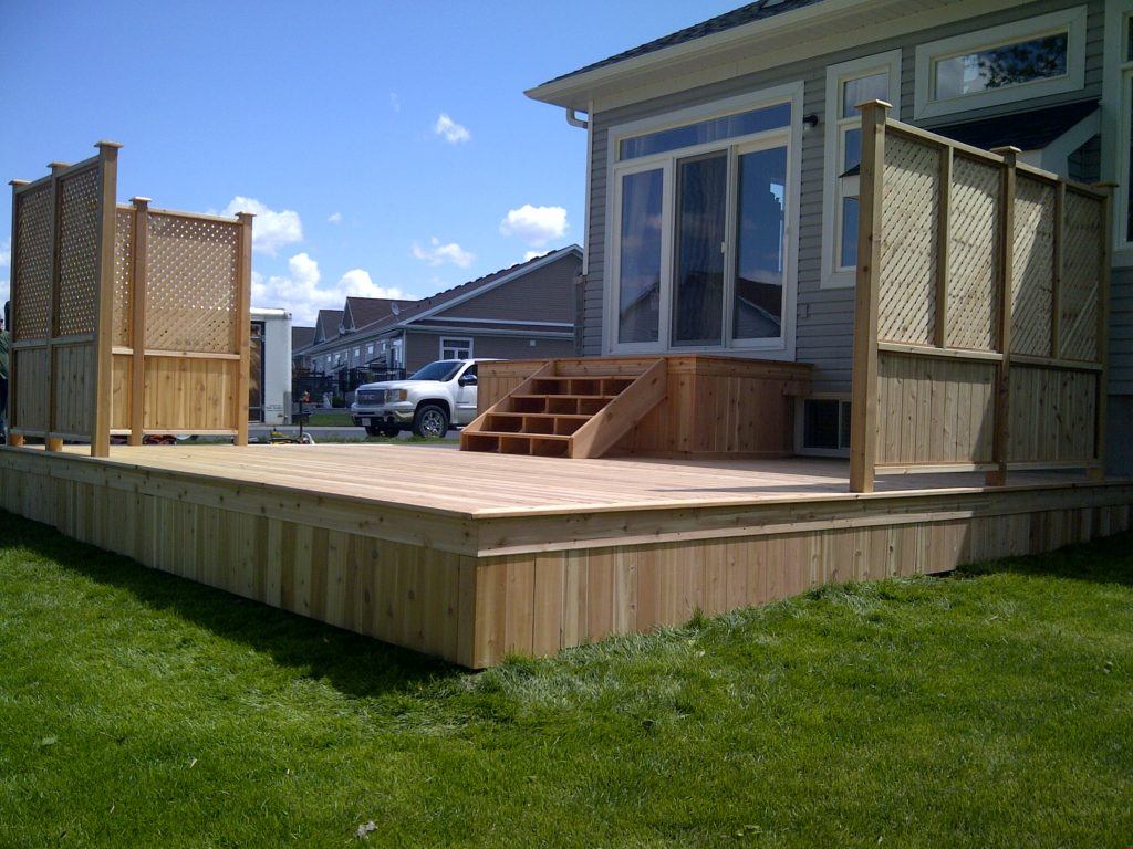 custom wooden deck with two corner fences and a platform with stairs from the house