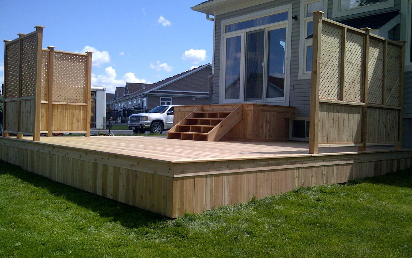 custom wooden deck with two corner fences and a platform with stairs from the house