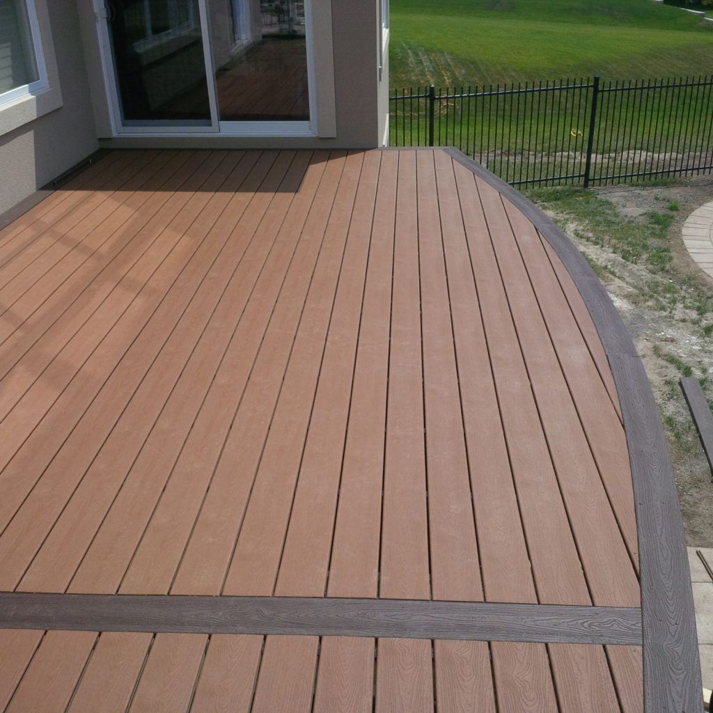 pristine newly constructed custom deck with curved edge facing backyard