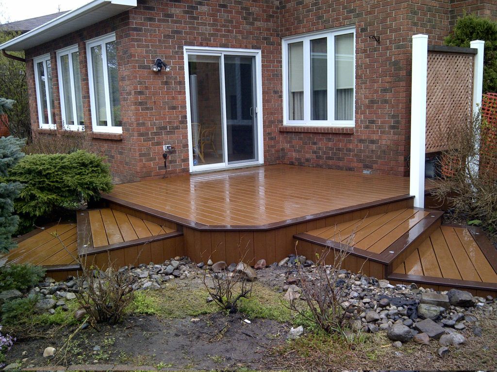 wet small custom deck with two sets of stairs leading in different directions from back door of house