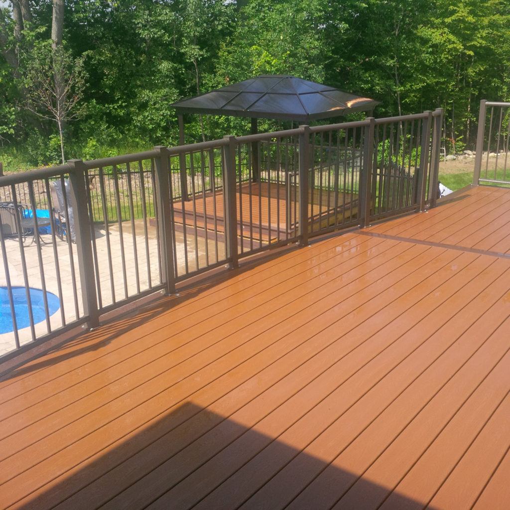 pristine custom deck with railings and a pergola in the background