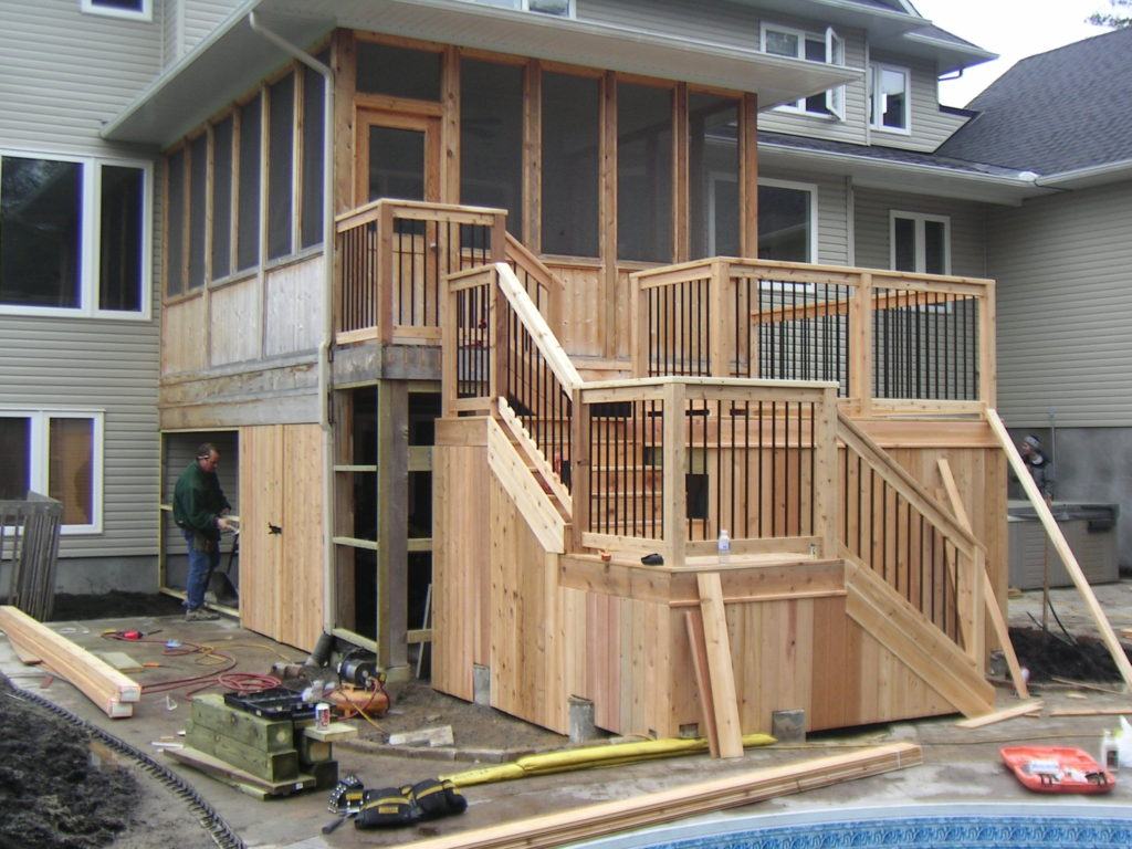 under construction two level wooden deck attached to sunroom