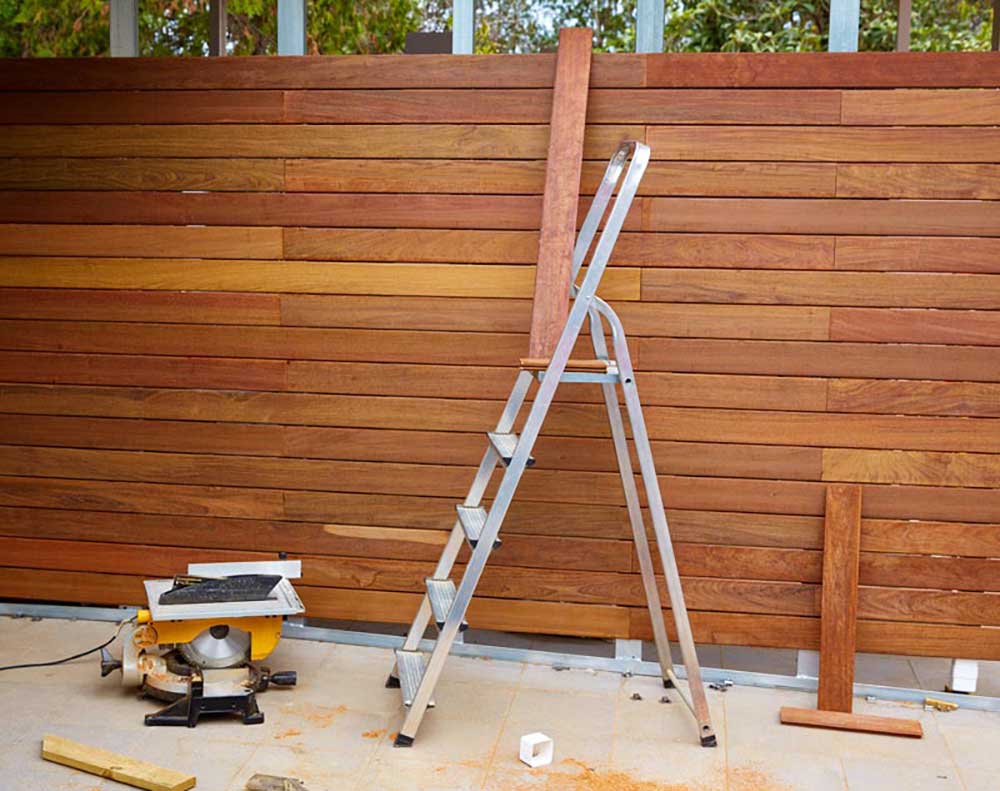 under construction fence with horizontal wood planks saw and ladder